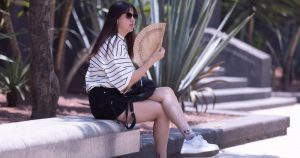 Una joven sentada a la sombra se abanica para refrescarse por las altas temperaturas registradas en el Valle de México, debido a que persiste la tercera ola de calor.