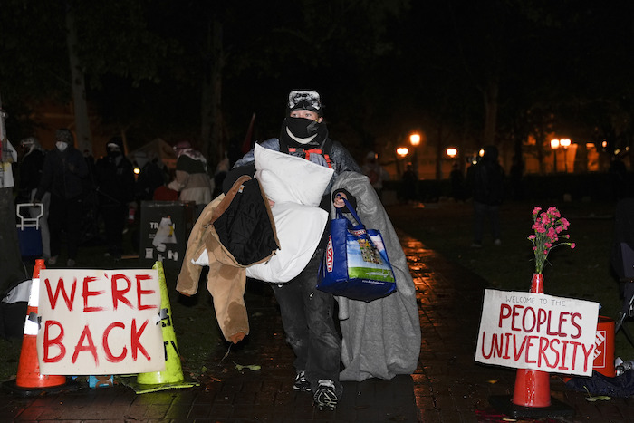 Personas con sus pertenencias abandonan un campamento instalado por manifestantes propalestinos tras la llegada de la policía para un operativo en el campus de la Universidad del Sur de California, el domingo 5 de mayo de 2024, en Los Ángeles.