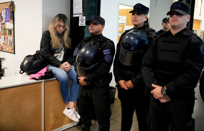 La empleada pública Florencia Ugarte sentada, mientras la policía impide que sus compañeros despedidos ingresen al Instituto Nacional contra la Discriminación, la Xenofobia y el Racismo (INADI) en Buenos Aires, Argentina, el miércoles 3 de abril de 2024.