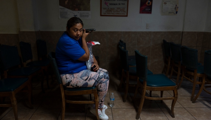 Mayra Mauricio, mexicana deportada de Estados Unidos, sostiene su celular junto al oído para escuchar un mensaje de un familiar mientras espera a cenar en la capilla del refugio para migrantes San Juan Bosco en Nogales, México, el martes 25 de junio de 2024. Muchos migrantes que no logran pasar el filtro son deportados a Nogales, una amplia ciudad en el lado mexicano del estado de Sonora, y terminan en el San Juan Bosco, donde un enorme ventilador en una antigua capilla ofrece alivio del sofocante calor estival.