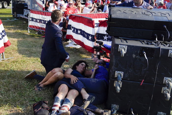 Civiles se cubren al tiempo que agentes del Servicio Secreto de Estados Unidos rodean al expresidente Donald Trump durante un acto de campaña, el sábado 13 de julio de 2024, en Butler, Pensilvania.