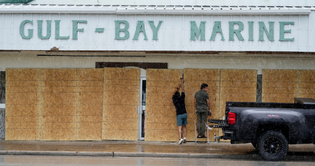 Doan Vu, izquierda, y Luan Nguyen, derecha, tapian las ventanas de su negocio en preparación para la llegada de la tormenta tropical "Beryl", el domingo 7 de julio de 2024, en Palacios, Texas.