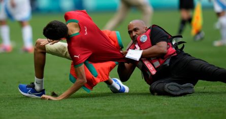 Un agente de seguridad atrapa a un hincha que invadió el campo de juego durante el encuentro de Argentina y Marruecos en el estadio Geoffroy-Guichard de Saint-Etienne, el miércoles 24 de julio de 2024.