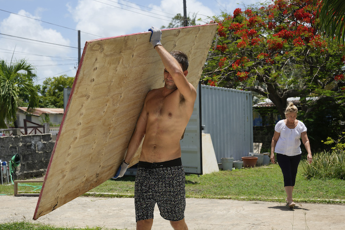 Un vecino carga un tablón de madera para cubrir las ventanas de su casa en preparación para el huracán "Beryl", en Bridgetown, Barbados, el domingo 30 de junio de 2024.