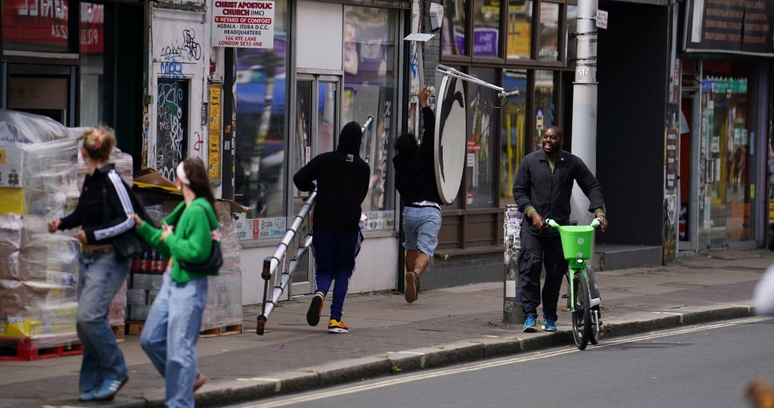 Se retiran corriendo con una nueva obra de arte de Banksy, que representa un lobo aullando pintado en una antena parabólica que se colocó en el techo de una tienda en Peckham, al sur de Londres, el jueves 8 de agosto de 2024. 