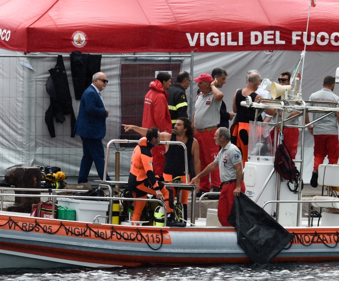 Bomberos y buzos italianos atracan en el puerto de Porticello, en el sur de Italia, el martes 20 de agosto de 2024, mientras los equipos de rescate regresan al lugar donde se hundió un superyate a causa de una tormenta para buscar a seis personas, entre ellas el magnate informático británico Mike Lynch, que se cree que siguen atrapadas en el casco a 50 metros bajo el agua. 