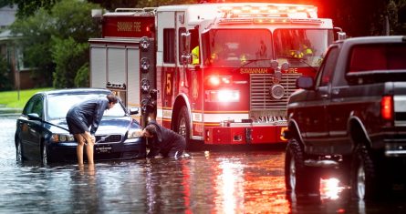 Dos personas atan un cabo a un auto varado en una calle anegada debido a las fuertes lluvias de la tormenta tropical Debby, el 5 de agosto de 2024, en Savannah, Georgia.