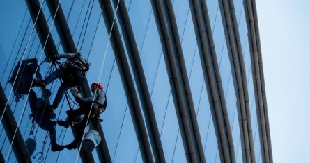 Dos limpiavidrios laboran en un edificio de Periférico Sur en la alcaldía Álvaro Obregón.