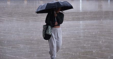 Una mujer se protege de la lluvia mientras camina por el pasillo central del Monumento a la Revolución en la Ciudad de México.