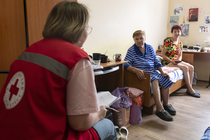 Una trabajadora de Cruz Roja, de espaldas a la cámara, escucha a personas evacuadas de los combates entre fuerzas rusas y ucranianas en la región de Kusk, en un alojamiento temporal en Kursk, Rusia, el domingo 11 de agosto de 2024.