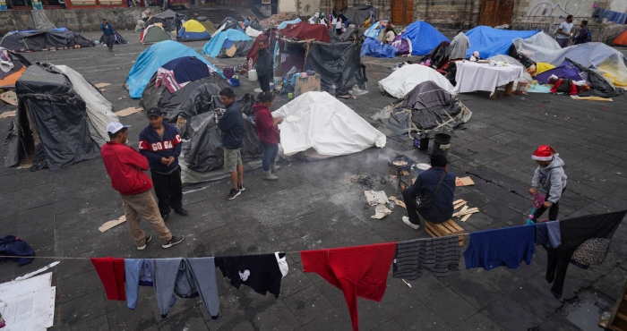 Migrantes se reúnen en un campamento instalado en la plaza de la parroquia de Santa Cruz y La Soledad, el 26 de diciembre de 2023, en el barrio de La Merced de Ciudad de México.