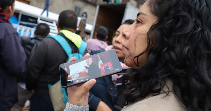 Una mujer escucha la conferencia de prensa de AMLO