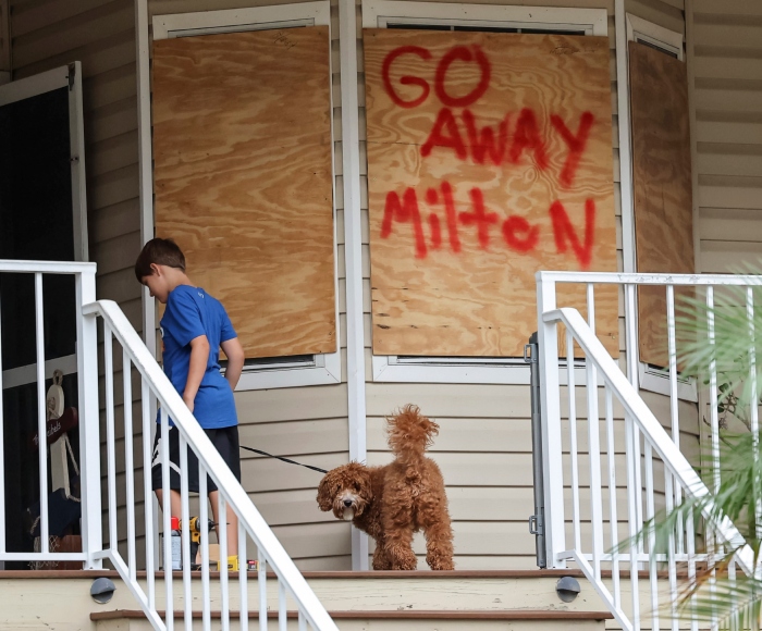 Noah Weibel y su perro, Cookie, suben las escaleras de su casa mientras su familia se prepara para la llegada del huracán Milton, el 7 de octubre de 2024, en Port Richey.