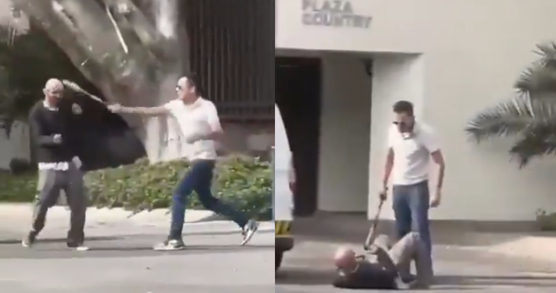 Ambos hombres se enfrentan en la calle; uno de ellos, vestido con camisa blanca y lentes oscuros, porta un bate de béisbol que usa para golpear al otro, de camisa negra, en la cabeza.