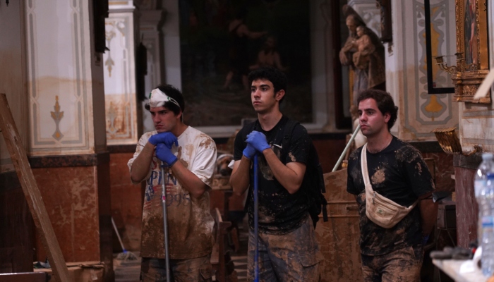 Tres jóvenes que han estado trabajando para limpiar los destrozos causados por inundaciones asisten a misa en la iglesia de San Jorge, el jueves 7 de noviembre de 2024, en Paiporta, España.