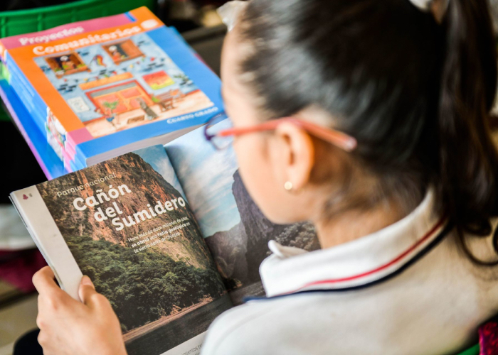 Una niña con los libros de texto gratuitos que reparte la SEP