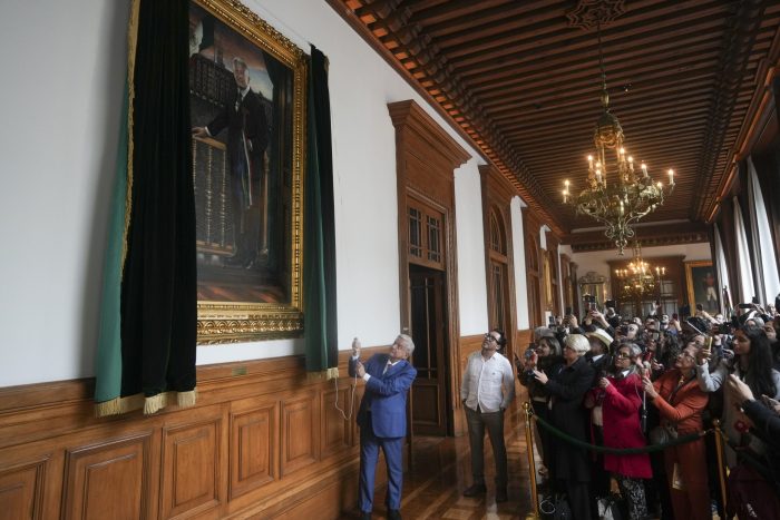 El entonces Presidente mexicano Andrés Manuel López Obrador revela un retrato suyo en Palacio Nacional.