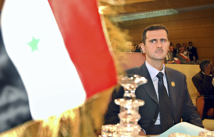 Bashar Assad mira a la bandera de su país.