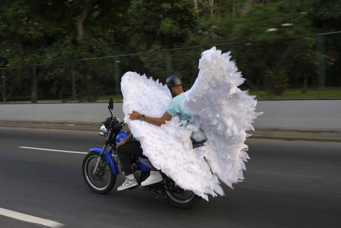 Dos personas llevando en una motocicleta alas de ángel en el carnaval en Caracas.