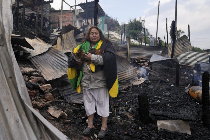 Verónica Kutdo carga a sus gallinas después de que su casa se quemara en Colombia.