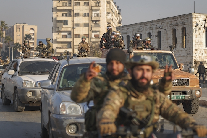 Combatientes de la oposición siria conducen por las calles.