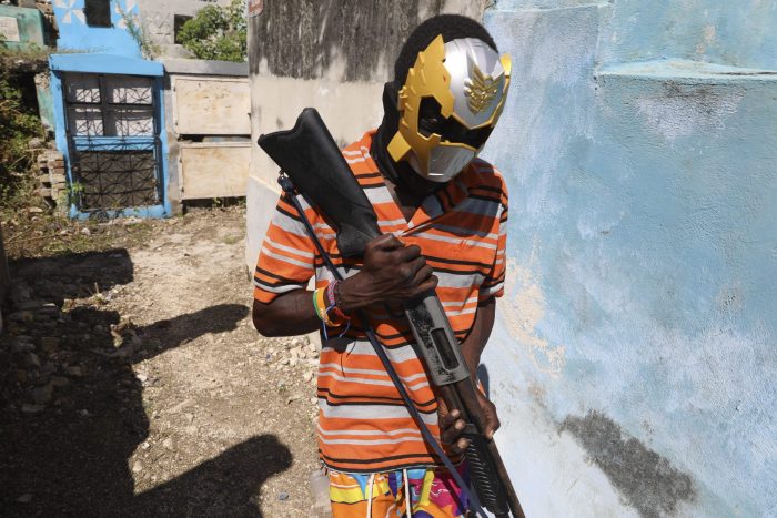 Un miembro de una pandilla enmascarado y armado posa para una foto en el Cementerio Nacional durante el festival Fete Gede.