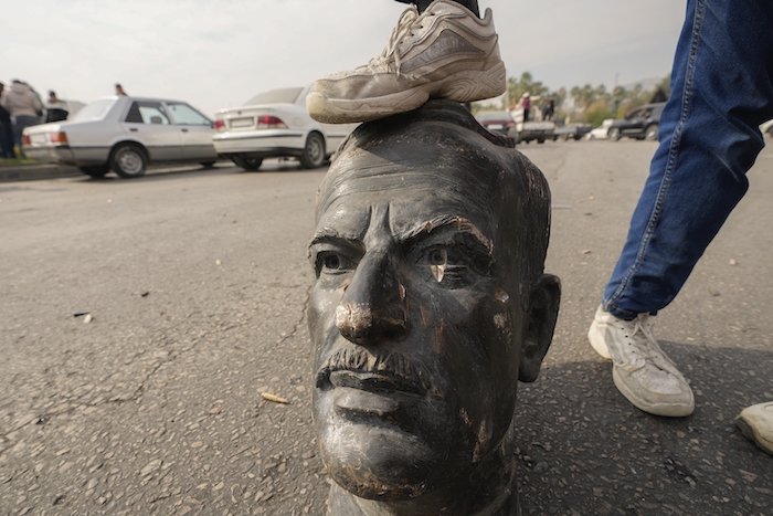 Un combatiente opositor pisa la cabeza de un busto roto del fallecido Hafez Assad.