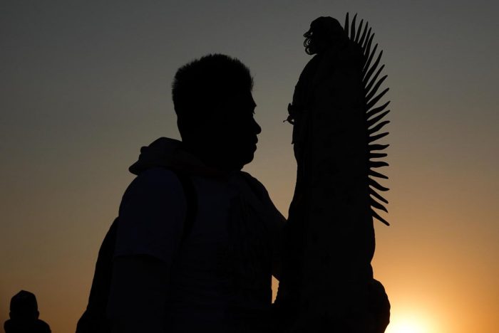 Un hombre sostiene la estatua de la Virgen de Guadalupe.